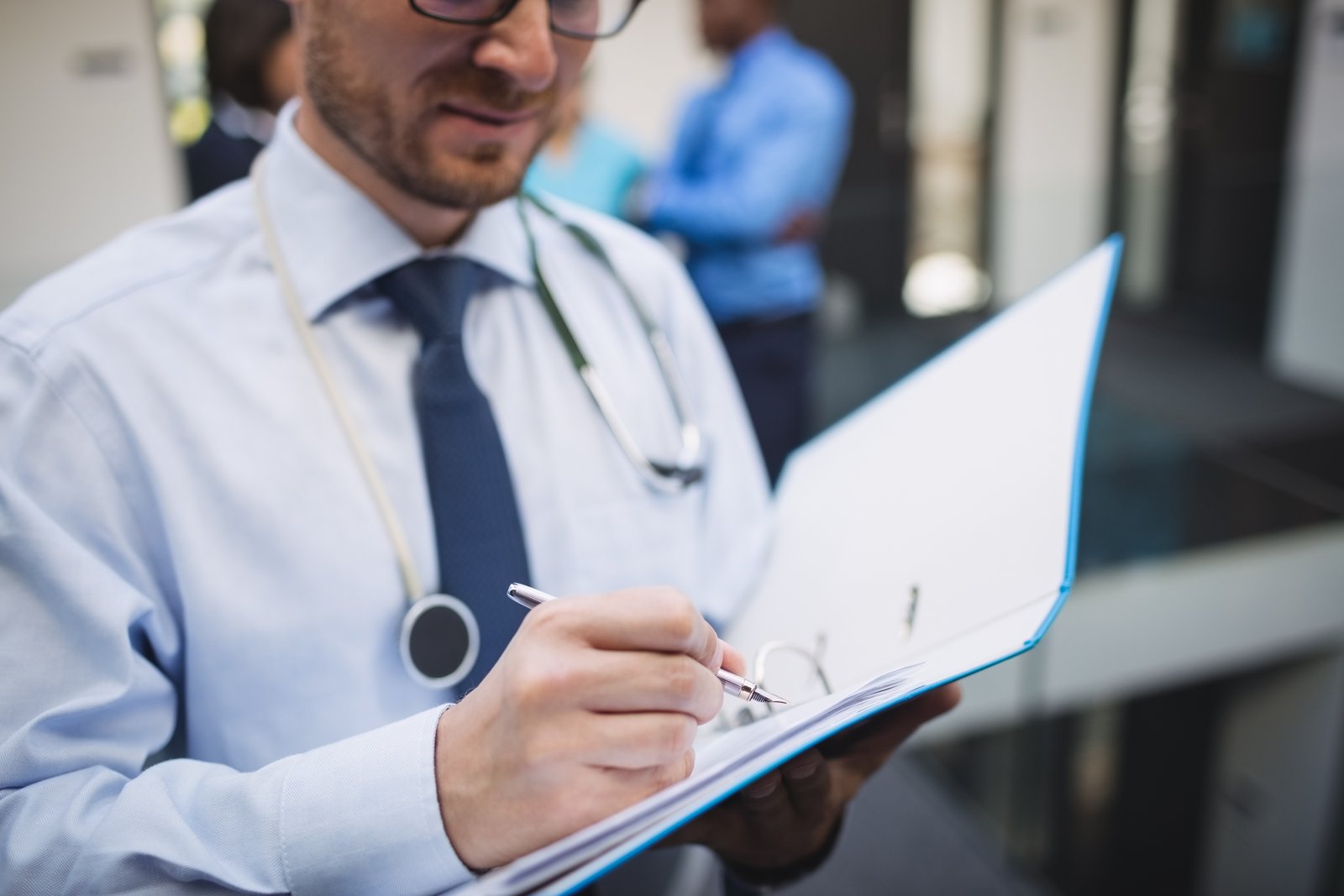 Médico escrevendo em prontuário